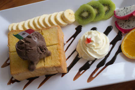 Honey Toast bread topped with ice cream, chocolate sevred with fruit and whipped cream,process colorの写真素材