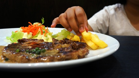 Kid eating grilled steakの写真素材