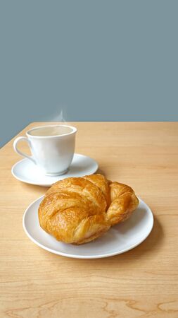Cup-of-cappuccino-with-croissant-and-a-pastel-blue-backgroundの写真素材
