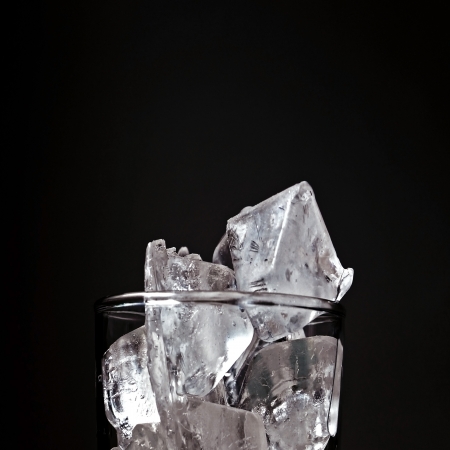 Ice cube in glass on black backgroundの写真素材