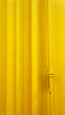 old yellow pipes on wall (vertical)の写真素材
