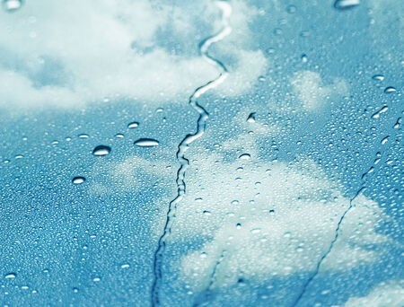 Rainsdrops on a window with a blue sky backgroundの写真素材