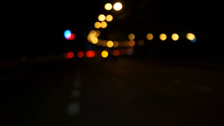 Bright circles from streetlamps on defocused photo of night streetの写真素材