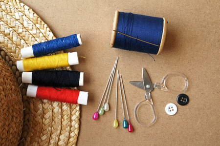 Sewing items  buttons, colorful fabrics, scissors, measuring tape, thimble, spools of thread on sewing patternの写真素材