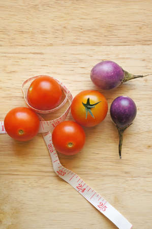 cherry tomatoes on wooden background with measuring tape (diet concept)の写真素材