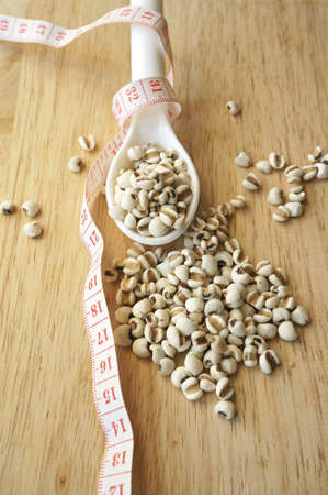 millet in spoon wrapping with measuring tape on wooden tableの写真素材
