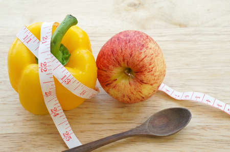 Vegetable diet. Yellow bell pepper with measuring tape and appleの写真素材