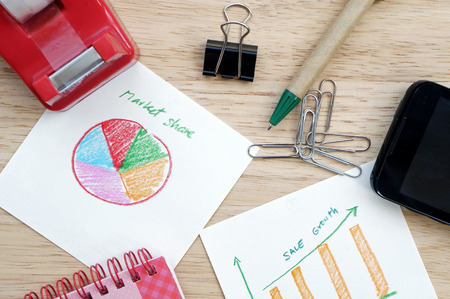 Business concept with pen, mobile phone and financial table and graph