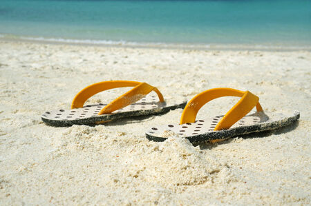 Summer vacation background with a pair of sandals on beachの写真素材