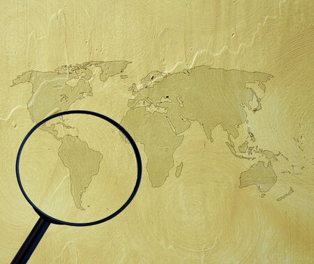 world map on cement wall with magnifying glassの写真素材