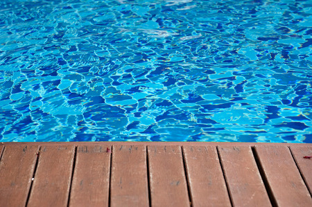 blue swimming pool with wood flooring stripes summer vacation