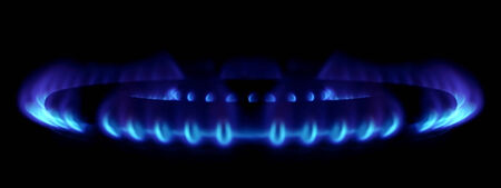 gas stove burner detail with blue flames and dark background