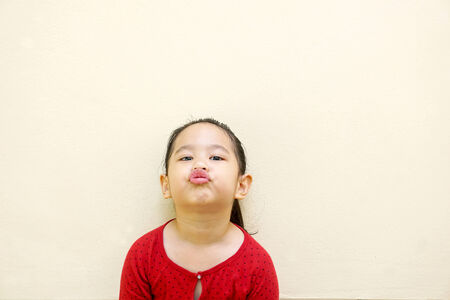 Portrait of girl in red shirt on white background. She looks into camera, lips depicting kissの写真素材