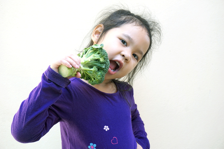 Little girl eating broccoli - healthy foodの写真素材