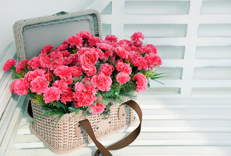Pink flowers in basket on white table.の写真素材