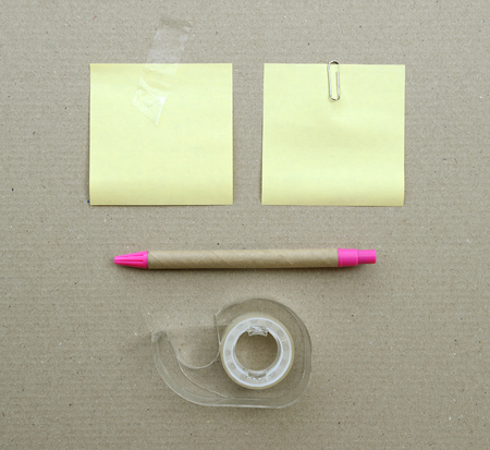 stationery supplies note paper pen paper clips and tape on brown paper background
