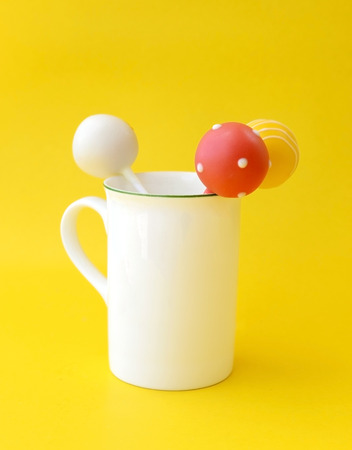 Lollipop in white cup, on yellow backgroundの写真素材