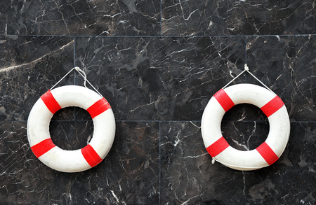 Lone red life ring, on the wall beside pool