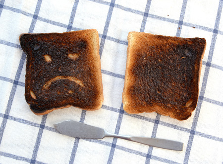 Sad and unhappy smiley made from toasted bread with knifeの写真素材