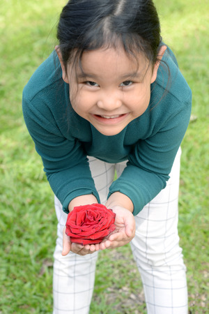 little girl with flower headband holding red rose in handsの写真素材