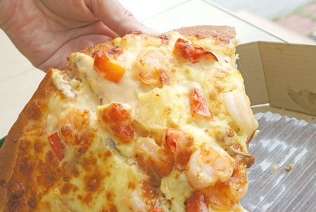 hand holding a slice of pizzaの写真素材