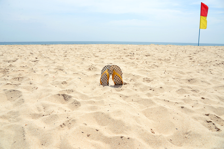 Flip flop on sand and safety flags sign on beachの写真素材