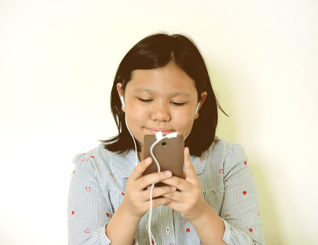 Smiling young girl listening music on smartphoneの写真素材