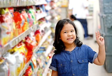 Adorable girl at shelves in supermarketの写真素材
