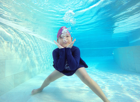 Happy little girl playing under water in pool.の写真素材
