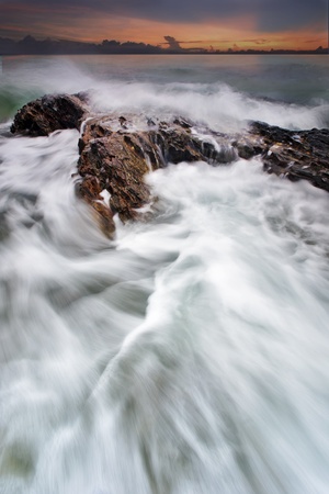 Sea waves and splash lash line impact rock on the beachの写真素材