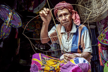 KOTA BHARU, MALAYSIA - FEBRUARY 19 : The master kite maker, Shafie Bin Jusoh works on his craft in a small hut near the Cahaya Bulan Beach, February 19, 2015 in Kota Bharu, Malaysiaのeditorial素材