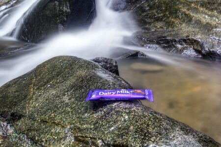SELANGOR, MALAYSIA - OCTOBER 25, 2015 : Cadbury Daily Milk Chocolate on the rocks with waterfall...