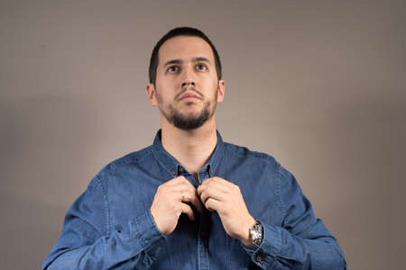 a gentleman with a beard buttoning a shirt