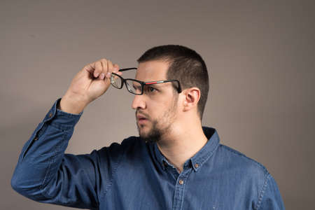 a man with a beard putting on glasses