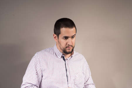 young man in plaid shirt looking pointlessの写真素材