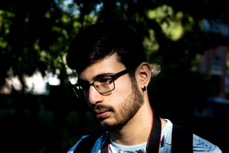 portrait of boy with glasses and beard in a park