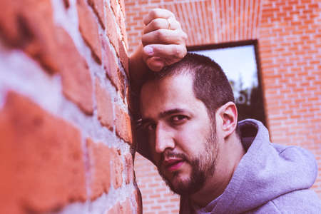 young man leaning against a brick wallの写真素材