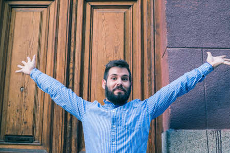 portrait of handsome cheerful young man with arms outstretched