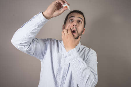 man throwing eye drops in his eyesの写真素材