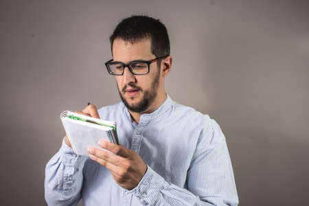 guy with glasses writing in a notebook