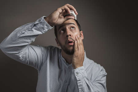 boy throwing eye drops in his eyesの写真素材