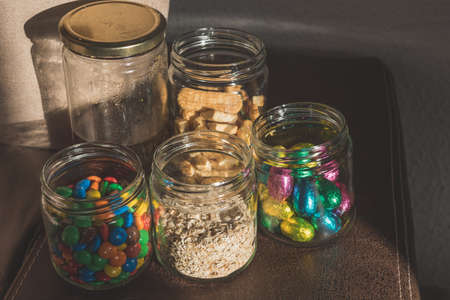 glass jars with chocolate candies, oatmeal, honey, cookies and chocolatesの写真素材
