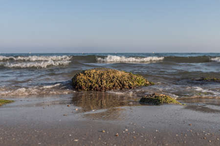 rock on the beach breaking the waves at sunset