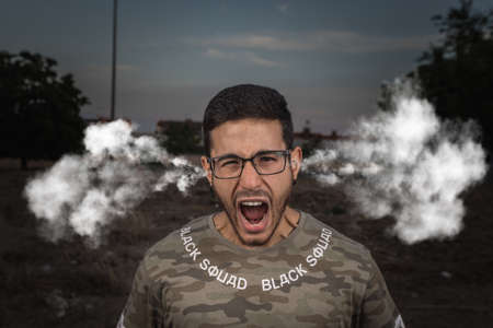 Young man screaming with euphoria, energy, enthusiasm and smoke coming out