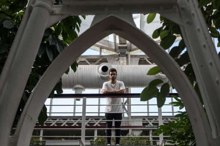 young man leaning over a balcony between an arch