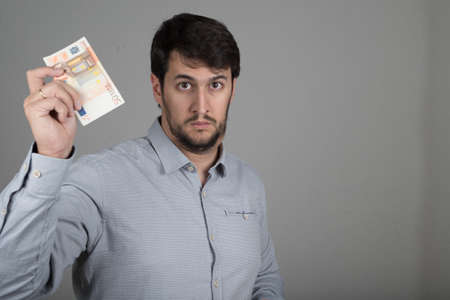 young man with a beard, with euros in his handの写真素材