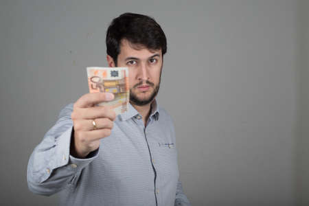 young man with a beard, with euros in his handの写真素材