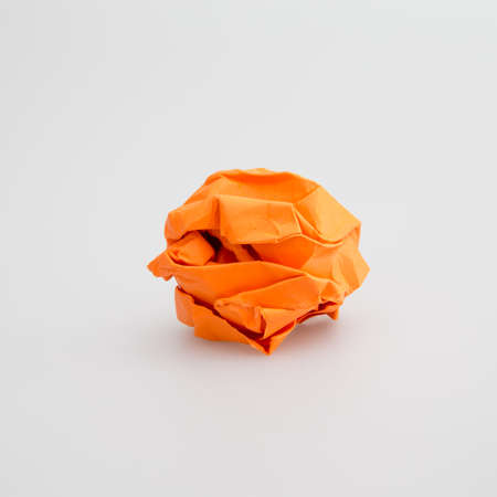 crumpled orange paper ball isolated white backgroundの写真素材