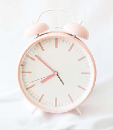 pink retro alarm clock on white fabricの写真素材