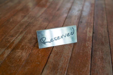 Reserved Metal Plate on the wooden Table. Reservation Seat at restuarant.